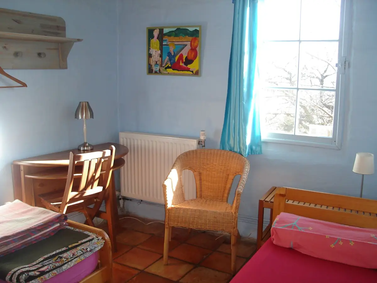 Une chambre claire avec un fauteuil en rotin et un rideau bleu